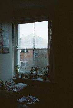 a living room filled with furniture next to a window covered in curtains and plants on the windowsill