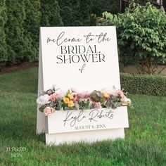 a sign that says welcome to the bridal shower with flowers on it in front of some bushes