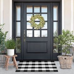 a black front door with a wreath and potted plants