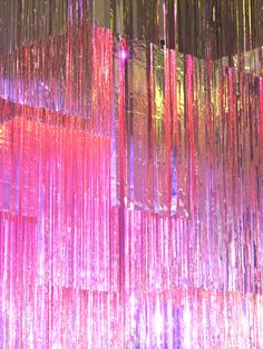 an abstract photo of pink and purple lights hanging from the ceiling in front of a window