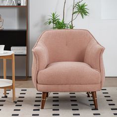 a pink chair sitting on top of a rug next to a potted plant in a living room