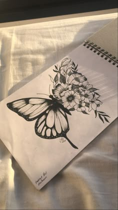 a drawing of a butterfly with flowers on it's back side, sitting on a sheet