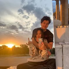 a man and woman sitting on the ground with their arms around each other as they take a selfie