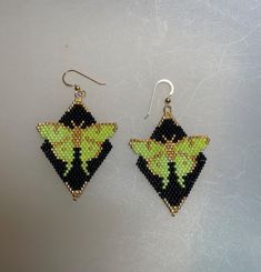 a pair of earrings with yellow and black designs on them sitting on a white surface