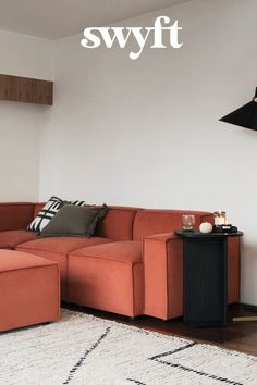 a living room with an orange couch and white rug on the floor next to a black lamp