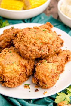 some fried food on a white plate next to corn