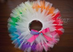 a colorful tutule wreath on a wooden floor with a ribbon tied around it