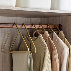 clothes hangers are hanging on the wall next to folded sweaters and pants in a closet