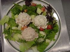 a white plate topped with lettuce and meatballs on top of a table