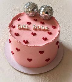 a pink cake with red hearts and two disco balls on top that says girl boss