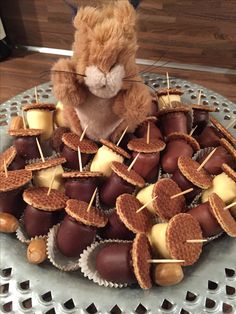 a teddy bear sitting on top of a plate filled with chocolate covered cookies and marshmallows