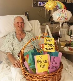 an elderly man sitting in a hospital bed next to a basket with signs on it