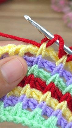 the crochet is being worked on by someone using a knitting needle to stitch