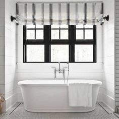 a white bath tub sitting next to a window in a bathroom