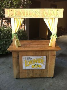 a lemonade stand with yellow drapes on the top, and a sign that says lemonade