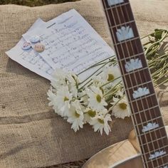 a guitar, sheet music and flowers are on the ground