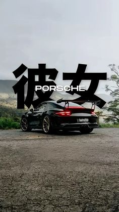 a black sports car parked on top of a dirt road next to the ocean with chinese characters above it