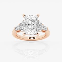 a cushion cut diamond ring with three side stones on the band and shoulders, set in 18k rose gold