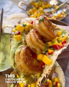 shrimp tacos with guacamole and mango salsa are served on tortillas