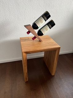 two bottles of wine sitting on top of a small wooden table next to a wall