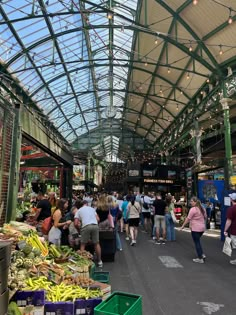 people are shopping in an indoor market with green roofing and glass windows on the ceiling