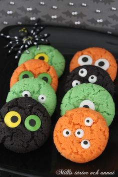 halloween cookies decorated with googly eyes and green, orange, and black frosting