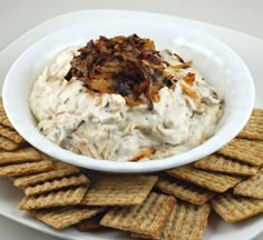 a white bowl filled with dip surrounded by crackers