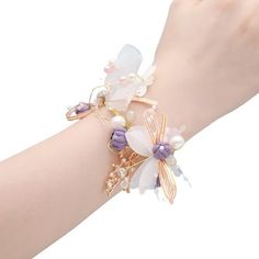 a woman's arm wearing a bracelet with flowers and pearls on the clasps