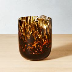 a glass filled with liquid sitting on top of a wooden table