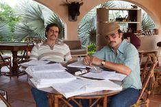 two men sitting at a table with papers on it