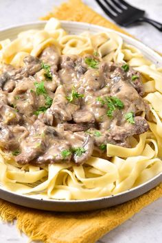 a white plate topped with pasta covered in gravy and meat on top of it