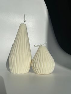 two white vases sitting next to each other on top of a table in front of a white wall