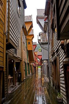 an alley way with wooden buildings on both sides and water running down the side walk