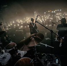 the band is playing on stage in front of an audience with lights behind them at night