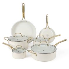 a set of white pots and pans with gold handles