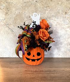 a pumpkin decorated with flowers and leaves on a table