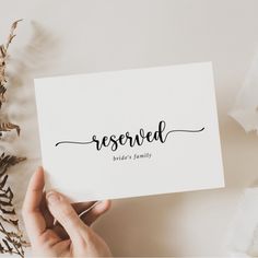 someone holding up a card with the word reserved written on it in cursive writing