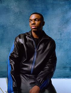 a man in a black leather jacket posing for a photo with his hand on his hip