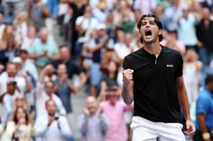 a male tennis player is celebrating his win in front of a crowd with people watching