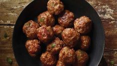 some meatballs are in a black bowl on a wooden table with the words cheesy sausage balls