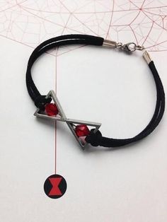 a black cord bracelet with two red beads and a silver triangle pendant on it's side