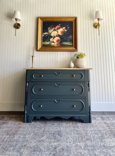 a painting on the wall above a dresser in a room with striped walls and carpet