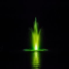 a green fountain is lit up in the dark