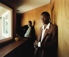 two men standing next to each other in front of a window