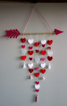 an arrow and heart mobile hanging on the wall