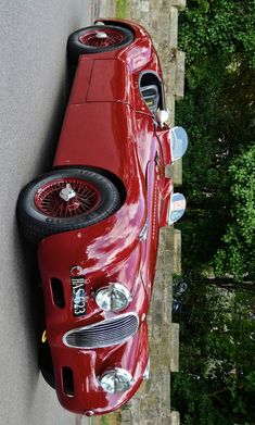 an old red car is parked on the side of the road