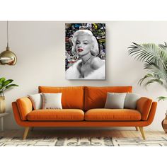 a living room with an orange couch and large painting on the wall above it's head