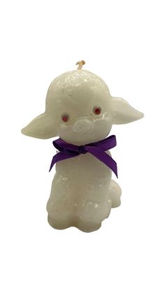 a small white candle with a purple ribbon around it's neck and eyes, on a white background