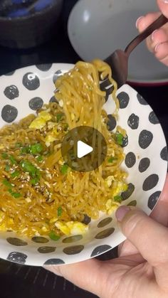 someone is eating noodles with chopsticks on a plate in front of the camera