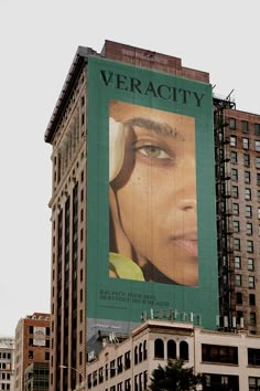 a large advertisement on the side of a tall building in new york city, with an image of a woman's face